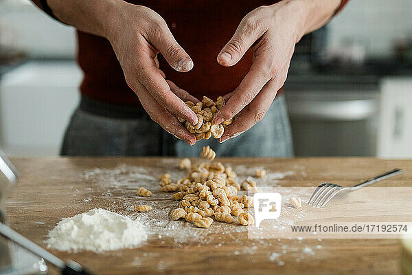 Masculine hands tossing and sprinkling flour on homemade pasta.