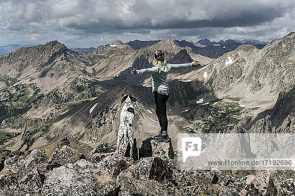 Female hiker hiking with dog on mountain against cloudy sky