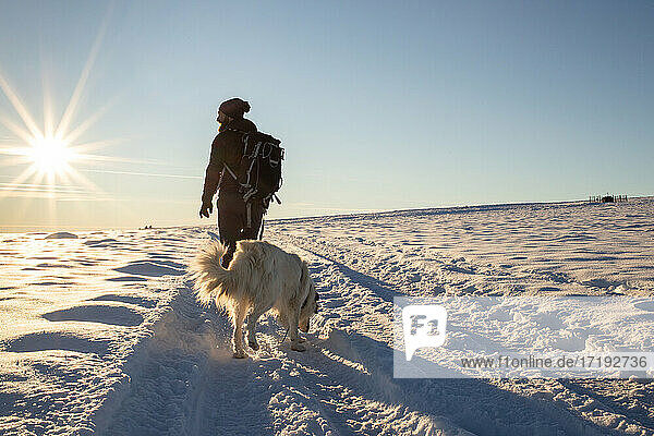 Mann mit Hund beim Trekking im Winterschnee