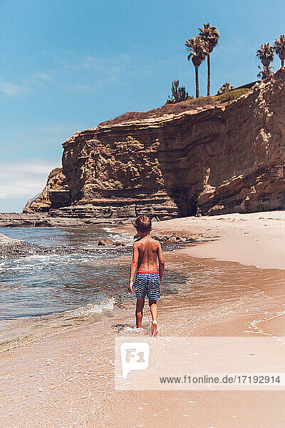 Junge geht allein an einem leeren Strand in Südkalifornien spazieren