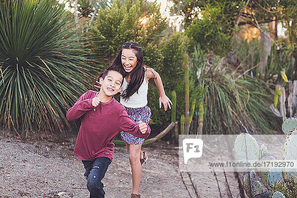 Sister and brother running in a cactus garden.