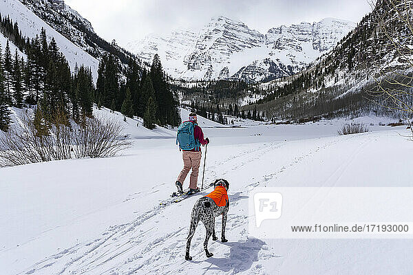 Young woman hiking with Pointer dog during winter