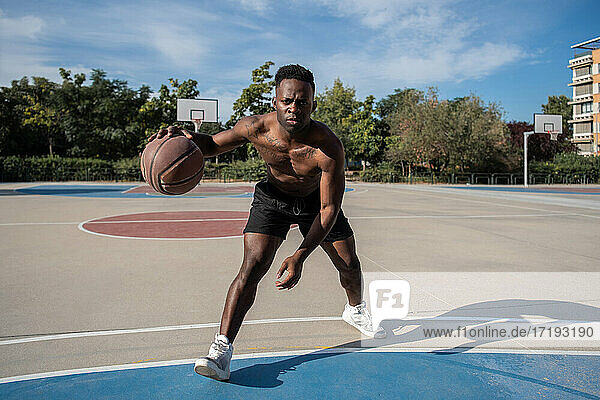Afroamerikanischer Sportler dribbelt Basketball auf dem Platz