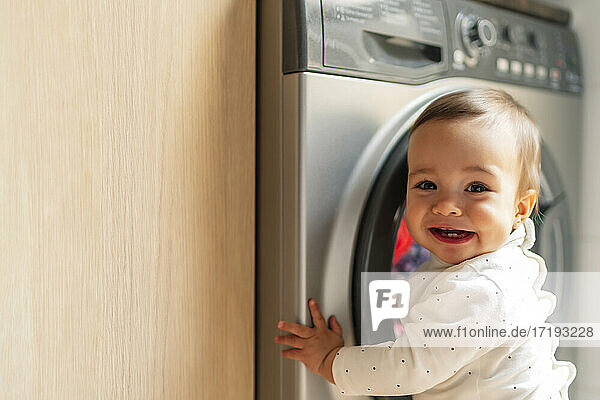 kleines Mädchen lachend mit Waschmaschine