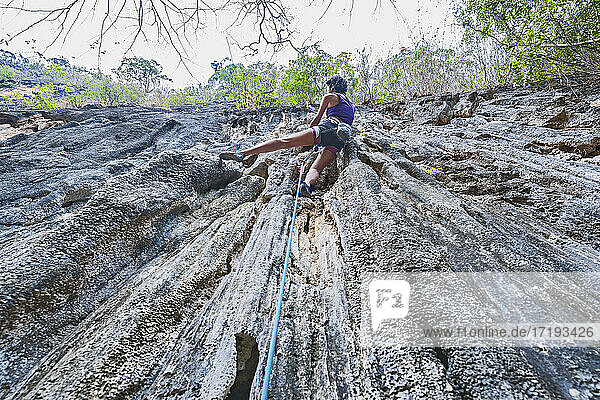 Frau klettert auf steilem Kalksteinfelsen in Laos