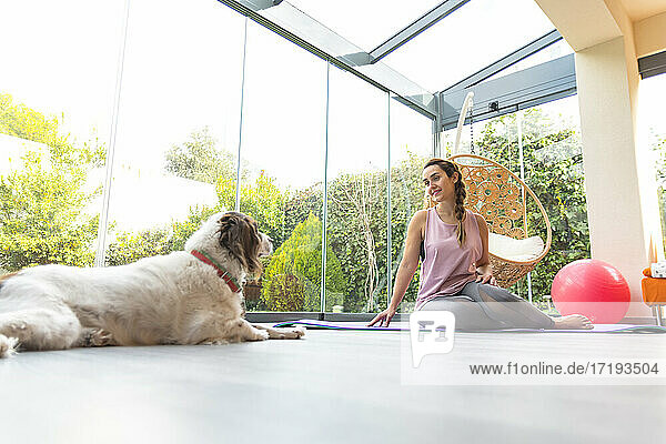 Frau mit ihrem Hund übt Yoga im Garten  Fitness zu Hause