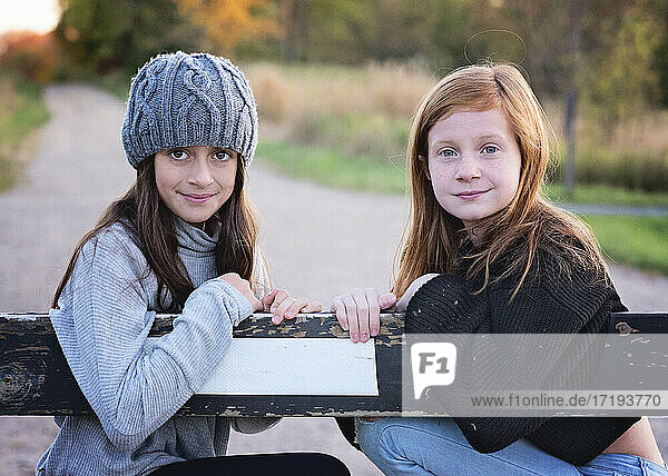 Zwei junge Mädchen in Pullovern im Freien auf einer Landstraße.