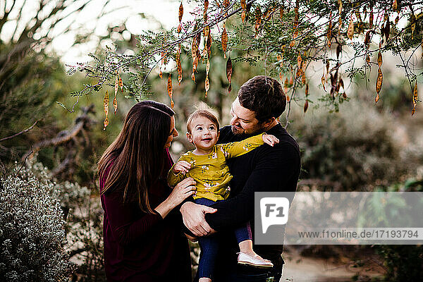 Mama & Papa halten lächelnde Tochter im Kaktusgarten in San Diego