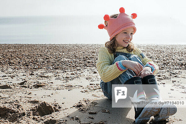 girl sat smiling on the beach wearing a crown on a sunny day in the UK