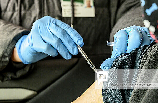 Eine Krankenschwester injiziert die Covid-19-Impfung in den Arm einer Frau in einer Drive-Thru-Ausgabestelle.