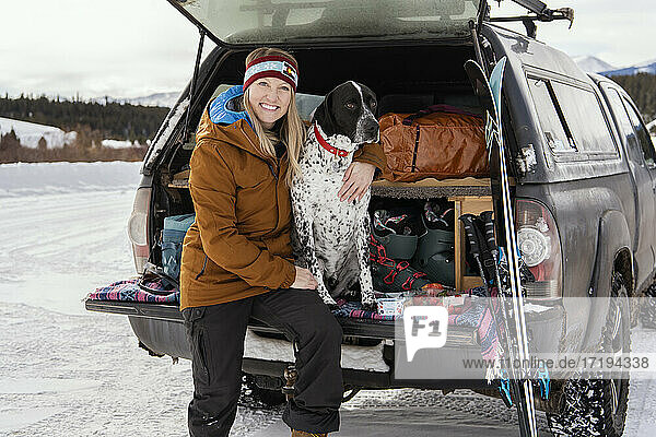 Lächelnde Frau mit Hund im Geländewagen im Winter
