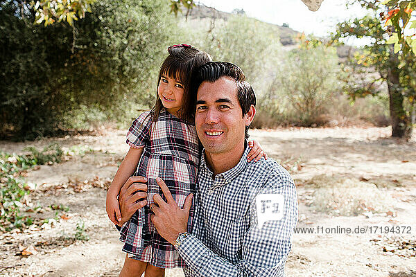 Vater und Tochter lächeln für die Kamera im Park in San Diego