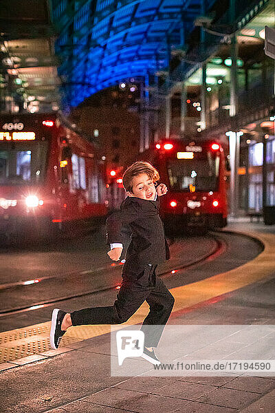 Ein Junge tanzt auf einem Bahnhof in der Innenstadt zur Nachtzeit.