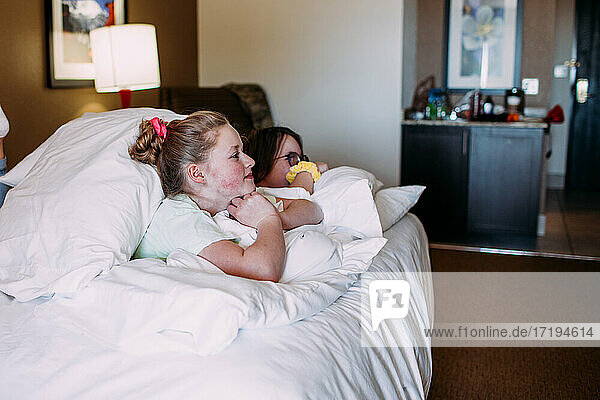 Zwei glückliche junge Mädchen entspannen sich auf einem Bett in einem Hotelzimmer