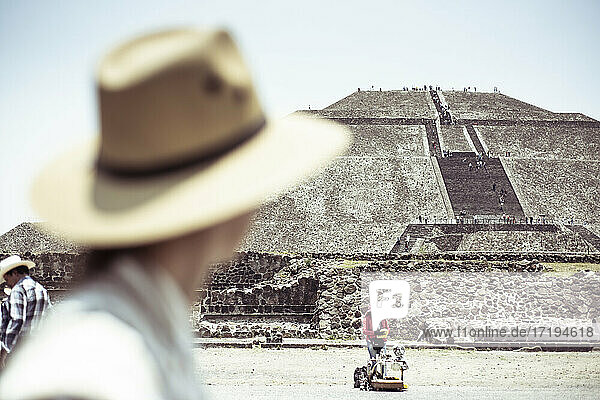Heilige Maya-Pyramide mit Tourist mit Hut vor Straßenverkäufer