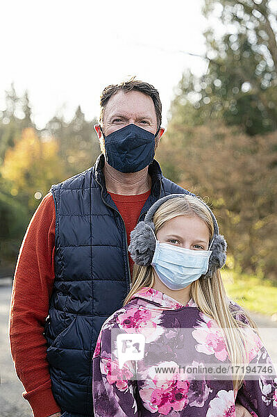 Mann und junges Mädchen mit Gesichtsmasken im Freien an einem Herbsttag in Seattle