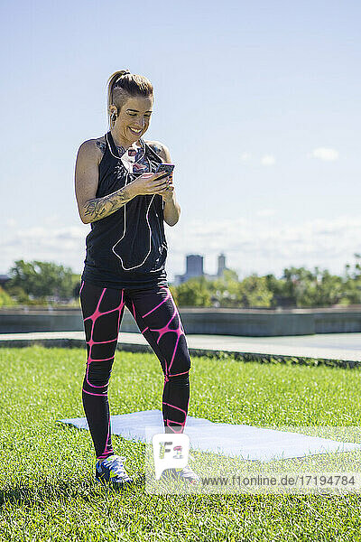 Junge  sportliche Frau benutzt ihr Smartphone beim Training