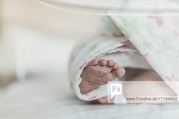 Nahaufnahme des neugeborenen Fußes im Stubenwagen im Krankenhaus nach der Geburt