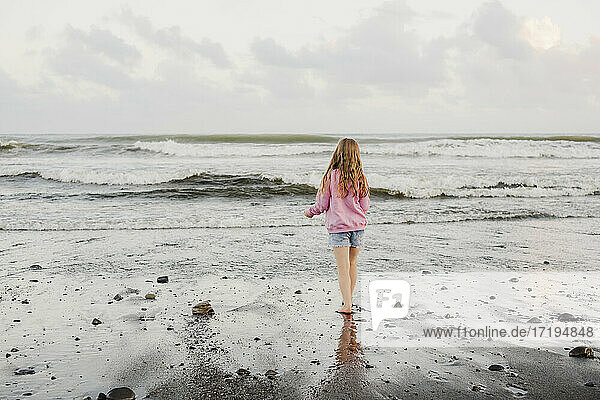Young girl standing at the waters edge at the beach