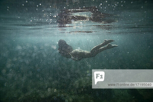 Weibchen schwimmt unter der Oberfläche des klaren blauen Ozeans mit Blasen