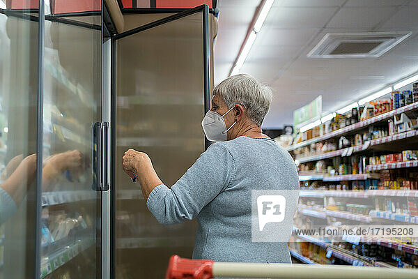 Kaukasische ältere Frau mit Gesichtsmaske beim Einkaufen im Supermarkt