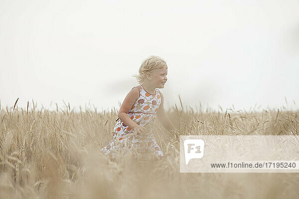Ein Mädchen läuft an einem sonnigen Sommertag durch ein Feld