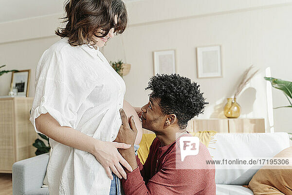 Zärtlicher schwarzer Mann küsst den Bauch einer schwangeren Frau