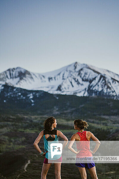 Two female friends stop to chat while trail running in the mountains