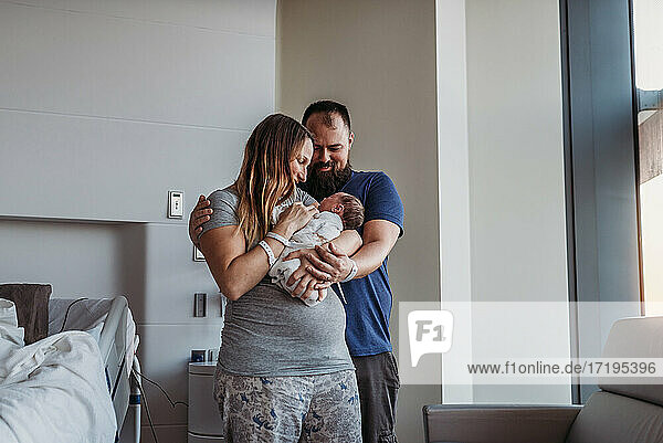 Newborn baby boy being cradled by new parents in birthing center