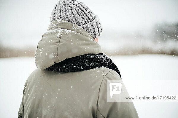 Frau steht auf verschneiter Straße und betrachtet eine Schneelandschaft