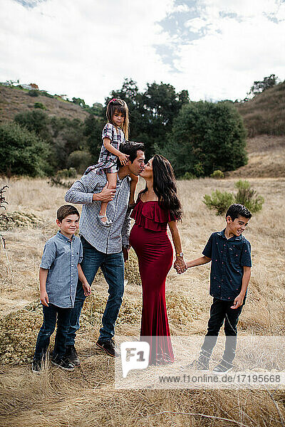 Mama und Papa küssen sich mit Kindern auf einem Feld in San Diego
