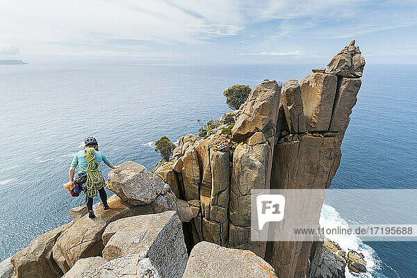 Eine Abenteurerin macht sich auf den Weg ins Unbekannte  bewaffnet mit Seilen und Kletterausrüstung  um Doleritfelsen in den Meeresklippen von Cape Raoul in Tasmanien  Australien  zu erkunden.