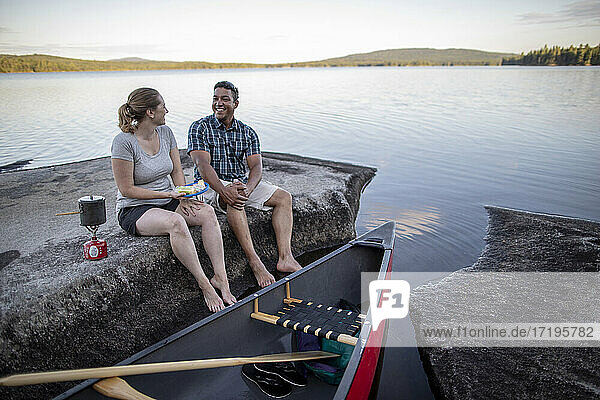 Ehepaar kocht und lacht während einer Pause von einer Kanutour  Maine