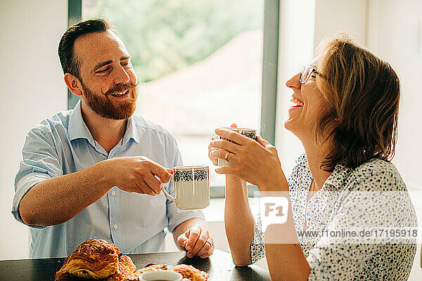 Verheiratetes Paar lächelt und lacht fröhlich beim Frühstück