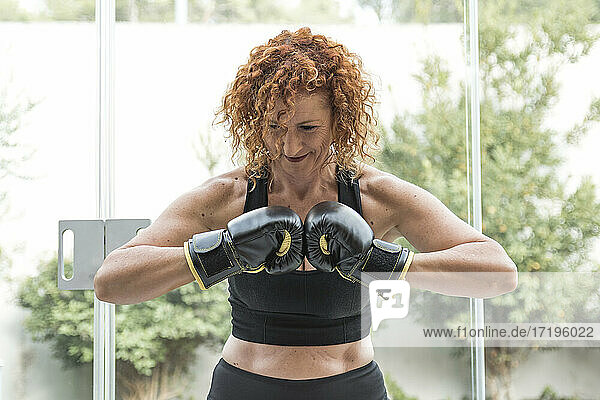 Reife rothaarige Frau stößt Boxhandschuhe an  Fitness zu Hause