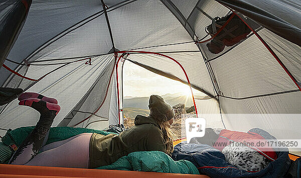 Woman camping in tent on mountain during vacation