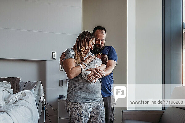 Newborn baby boy being cradled by new parents in birthing center