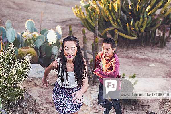 Bruder und Schwester spielen Fangen in einem Kaktusgarten.