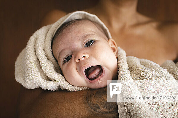 Ein wunderschönes Baby in ein Handtuch gewickelt  das den Mund mit seiner Mutter öffnet
