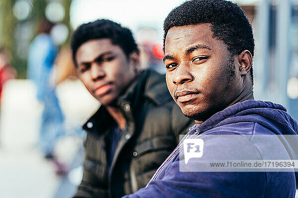 Portrait of two African-American friends sitting in an urban space.
