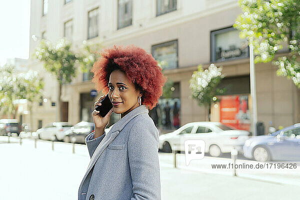schöne Frau mit Afro-Haar  die mit ihrem Smartphone spricht
