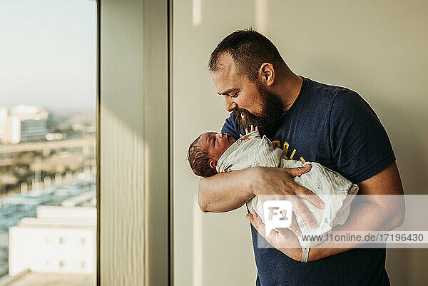 Lifestyle portrait of dad holding newborn baby boy in birthing center