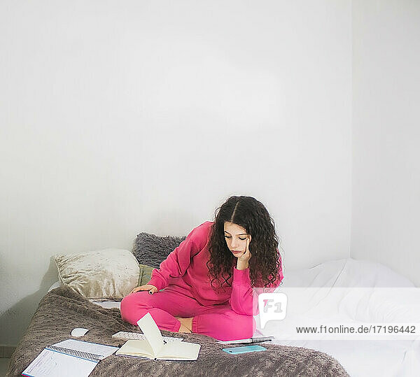 junge Frau im Bett  die besorgt arbeitet oder studiert