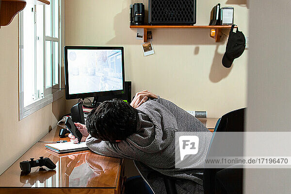 Gelangweilter Mann  der während eines langen Tages ein Telefon in einem Raum voller Technik benutzt
