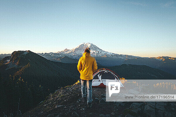 Ein Mann geht zu einem Zelt auf dem Gipfel eines Berges in der Nähe des Mt. Rainier