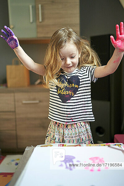 Glückliches kleines Mädchen Künstlerin mit gemalten Palmen feiern ihre Kunstwerk auf weißem Blatt Papier.