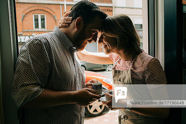 Young couple in love drinking coffee  smiling while standing at door