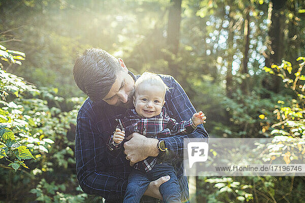 Father holding  loving young son outdoors.