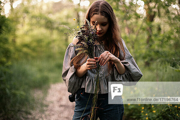 Teenager-Mädchen mit einem Strauß Wildblumen im Wald stehend