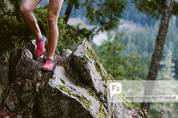 Die Beine einer Frau sind beim Laufen über scharfe Felsen in den Bergen zu sehen